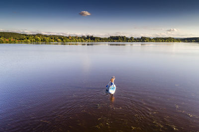 Rear view of man standing in lake against sky