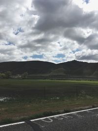 Road by field against sky