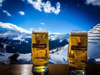 Close-up of beer glass against blue sky