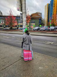 Rear view of woman walking on road in city