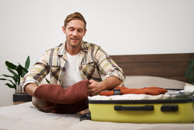 Portrait of young man sitting on sofa at home