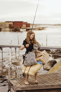 Pre-adolescent girl with picnic things standing on jetty