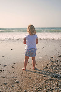 Rear view of girl on beach against sky