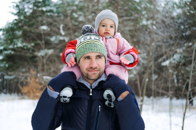 Portrait of happy father and baby toddler daughter on winter nature background. man and baby girl