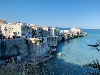 High angle view of buildings by sea against clear sky