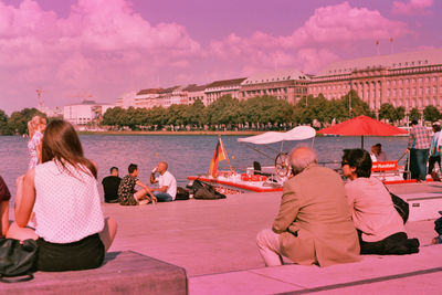 Woman sitting on bench against cloudy sky