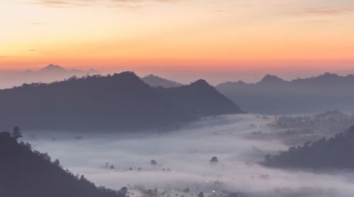 Scenic view of silhouette mountains against orange sky