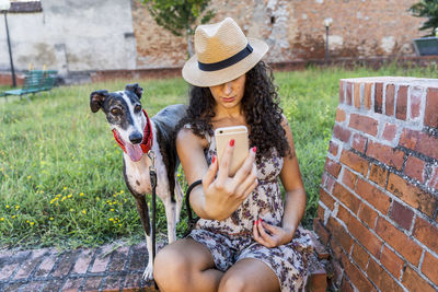 Woman taking selfie with dog while sitting outdoors
