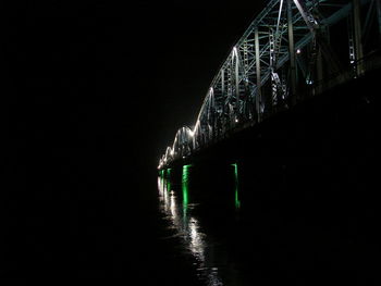 Low angle view of illuminated bridge over sea against sky at night