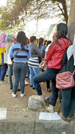 Rear view of people standing against the wall