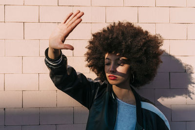 Portrait of young woman standing against wall