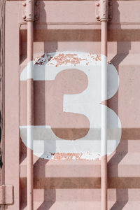 White silk-screen printing of number 3 on a pink shipping container