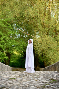 Rear view of woman in white  standing on path naer forest