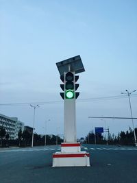 Illuminated traffic light on street against sky