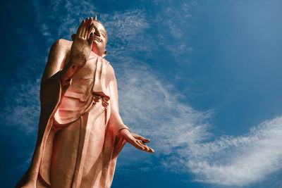 Low angle view of woman standing against blue sky