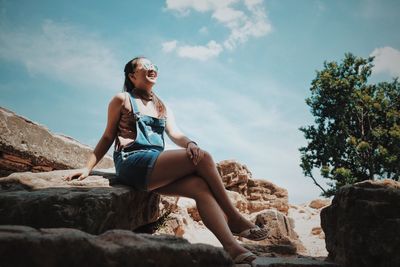 Low angle view of woman sitting on sunny day