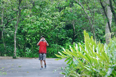 Boy photographing against plants and trees