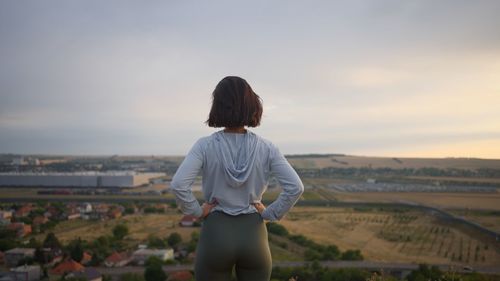 Rear view of woman standing against sky during sunset