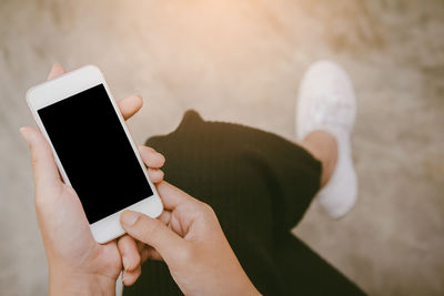 Low section of woman using mobile phone outdoors