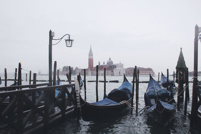 Gondolas moored at sea against sky