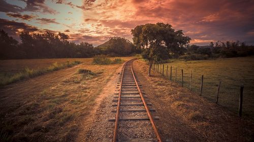 Railroad tracks against sky during sunset