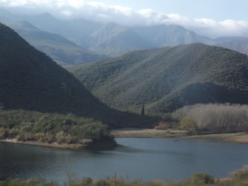 Scenic view of river and mountains against sky