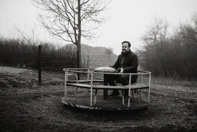 Man sitting on a carousel on a playground 