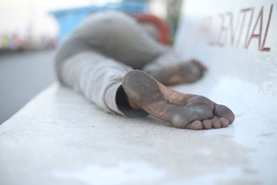 Low section of man with dirty feet lying down