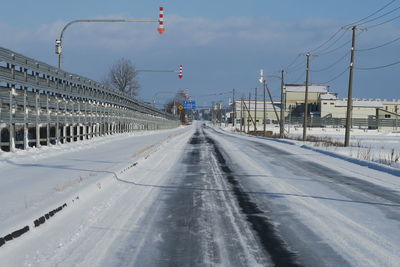 Road by snow covered city against sky