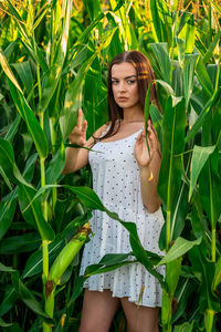 Portrait of young woman standing amidst plants