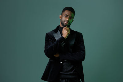 Portrait of young man standing against black background