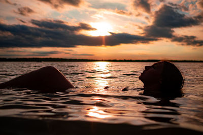 Woman floating in waves at sunset