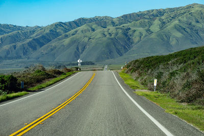 Road leading towards mountains against sky