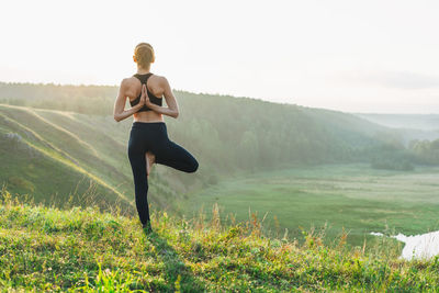 Young woman girl practice yoga looking on beautiful landscape on early morning