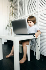 Cute boy using laptop at table