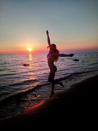 Woman standing at beach during sunset