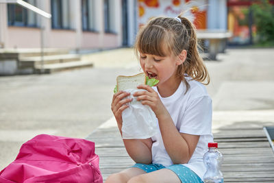 A girl eats a homemade sandwich in the schoolyard. nutrition for children during their studies.