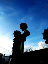 Low angle view of silhouette boy against sky