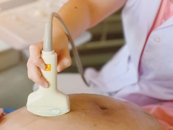 Close-up of doctor examining pregnant woman with ultrasound at hospital