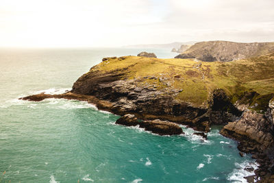 Scenic view of sea by cliff against sky