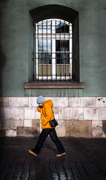 Full length rear view of woman walking against building