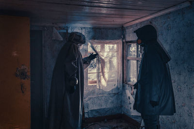 Fictional movie poster. people with flashlights, masks and protective clothing inspect old house. 
