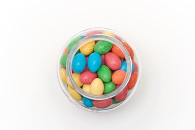 Close-up of multi colored candies in bowl against white background