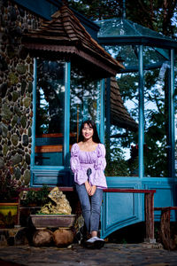 Portrait of smiling woman standing against built structure