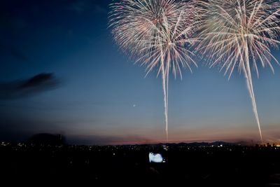 Firework display over city against sky at night