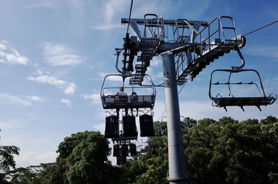 Low angle view of ski lifts and trees against sky