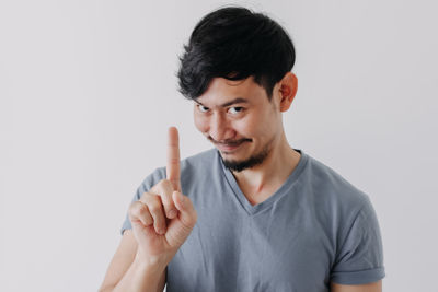 Portrait of smiling young man holding camera against white background