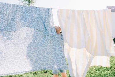 Young boy hiding in the washing drying on a sunny day at home