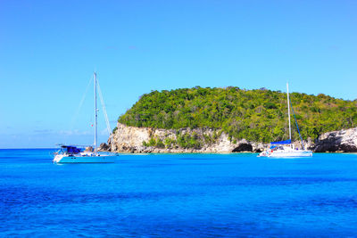 Sailboat sailing on sea against clear blue sky