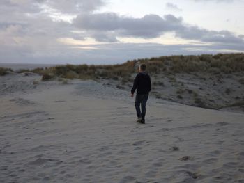 Man standing on landscape against cloudy sky